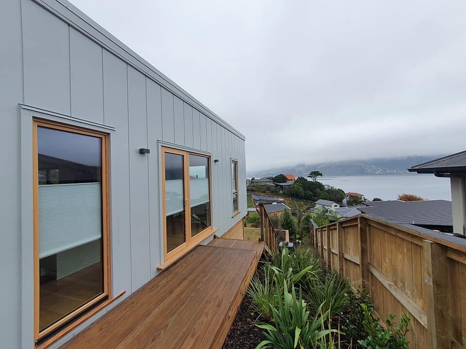 New extension with grey cladding and a timber deck looking out to the harbour