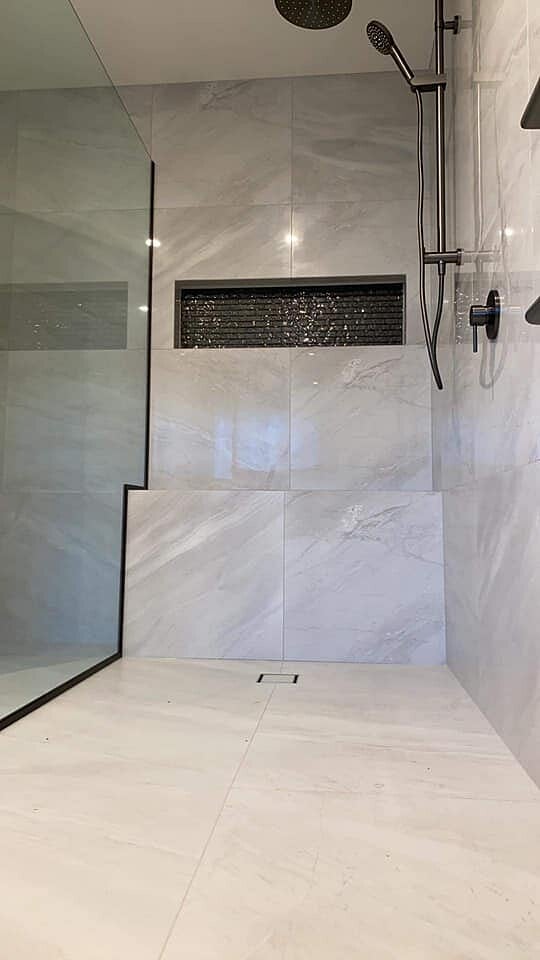 Tiled walk-in shower with a mosaic niche and level entry